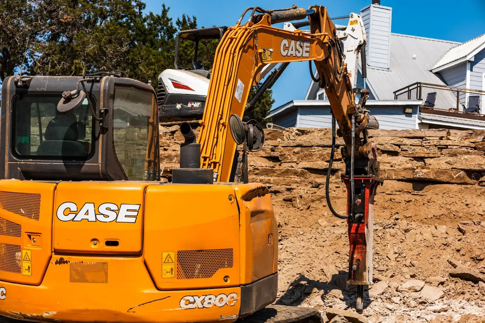 Excavator with breaker on a steep limestone lot